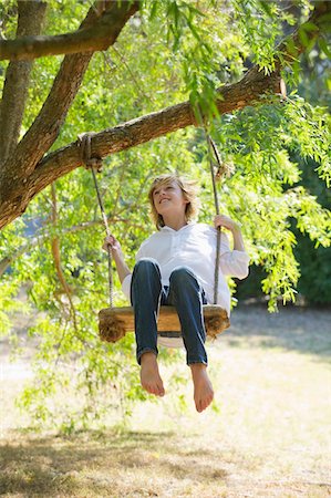 people sitting on branch tree - Happy little boy swinging on tree Stock Photo - Premium Royalty-Free, Code: 6108-05872716