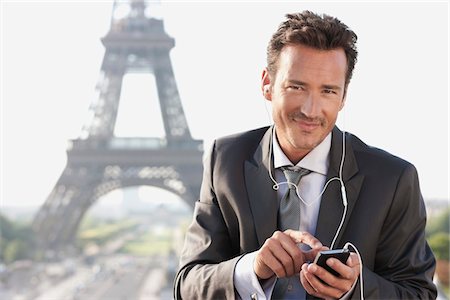 Homme d'affaires à l'aide d'un téléphone mobile avec la tour Eiffel en arrière-plan, Paris, Ile-de-France, France Photographie de stock - Premium Libres de Droits, Code: 6108-05872869