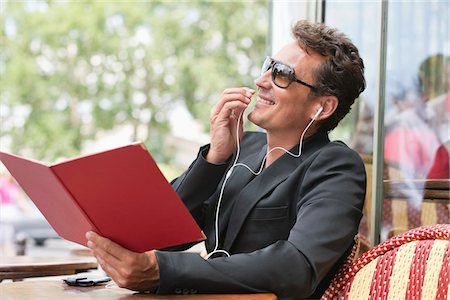 Man holding a menu and talking on a mobile phone in a restaurant, Paris, Ile-de-France, France Stock Photo - Premium Royalty-Free, Code: 6108-05872886