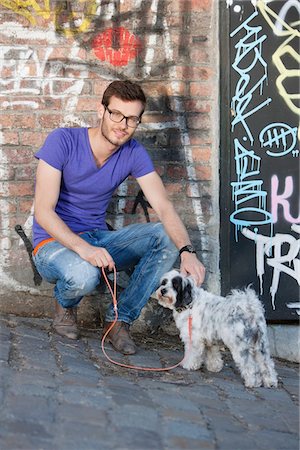 Homme avec un chiot devant un mur de graffiti, Paris, Ile-de-France, France Photographie de stock - Premium Libres de Droits, Code: 6108-05873023