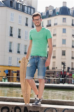 Man standing on the ledge of a canal with a skateboard, Canal St Martin, Paris, Ile-de-France, France Stock Photo - Premium Royalty-Free, Code: 6108-05873102