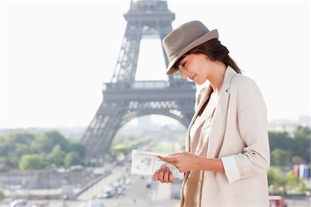 read and paris - Woman reading a guide book with the Eiffel Tower in the background, Paris, Ile-de-France, France Stock Photo - Premium Royalty-Free, Code: 6108-05873285