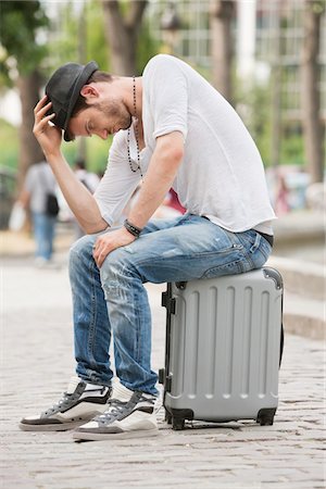 Man sitting on the suitcase at the roadside, Paris, Ile-de-France, France Fotografie stock - Premium Royalty-Free, Codice: 6108-05873238