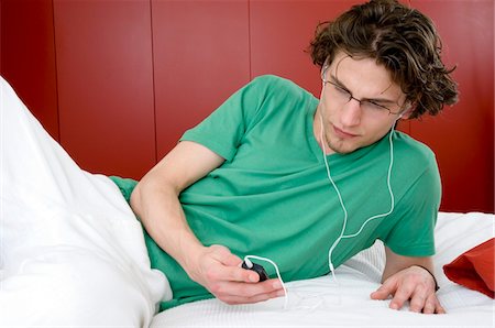 simsearch:6108-05856112,k - Homme à l'écoute de MP3 player, couché sur un lit Photographie de stock - Premium Libres de Droits, Code: 6108-05873354