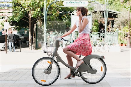 Femme enfourcher une bicyclette et parler sur un téléphone mobile, Paris, Ile-de-France, France Photographie de stock - Premium Libres de Droits, Code: 6108-05873323