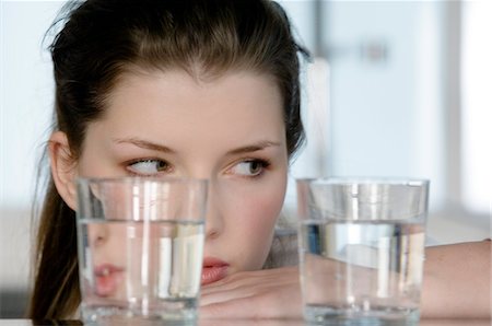 dieting - Portrait of a young woman looking at 2 glasses of water Stock Photo - Premium Royalty-Free, Code: 6108-05873477