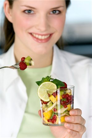 fork fruit - Portrait of a young woman eating fruit salad Stock Photo - Premium Royalty-Free, Code: 6108-05873474