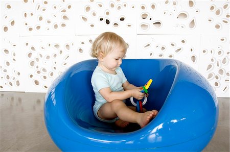 Little boy playing, sitting in a blue chair Stock Photo - Premium Royalty-Free, Code: 6108-05873410