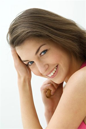 Portrait of a young woman brushing her hair Stock Photo - Premium Royalty-Free, Code: 6108-05873437