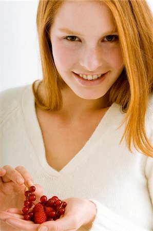 Portrait of a young woman holding berry fruits and smiling Stock Photo - Premium Royalty-Free, Code: 6108-05873600