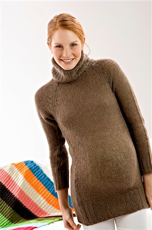 sweater - Portrait of a pregnant young woman standing and smiling Stock Photo - Premium Royalty-Free, Code: 6108-05873627