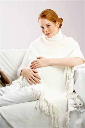 enceinte - Portrait d'une femme enceinte de jeune assis sur un canapé et souriant Photographie de stock - Premium Libres de Droits, Code: 6108-05873624