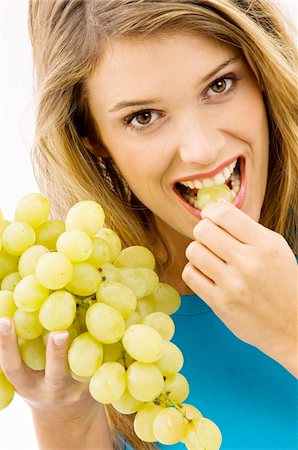 Portrait of a young woman eating grapes Stock Photo - Premium Royalty-Free, Code: 6108-05873633