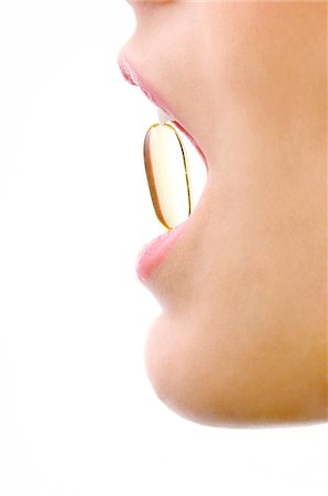 eat mouth closeup - Close-up of a woman's mouth with a capsule between her teeth Stock Photo - Premium Royalty-Free, Code: 6108-05873631