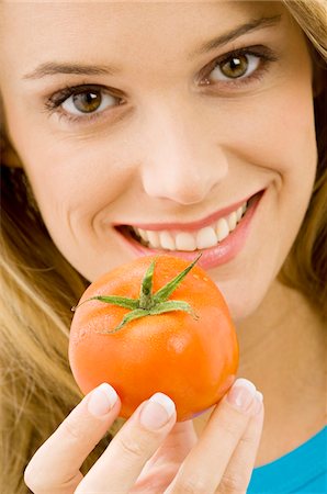 simsearch:6108-05861191,k - Portrait of a young woman holding a tomato and smiling Foto de stock - Sin royalties Premium, Código: 6108-05873634
