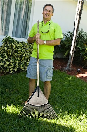 Man holding a rake in the lawn Stock Photo - Premium Royalty-Free, Code: 6108-05873751
