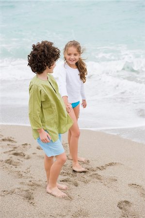 Boy and a girl standing with holding hands on the beach Foto de stock - Sin royalties Premium, Código: 6108-05873996