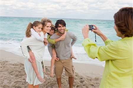 Woman taking a picture of her family with a digital camera Stock Photo - Premium Royalty-Free, Code: 6108-05873999