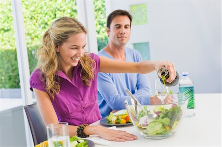 Woman pouring salad oil in salad and smiling Stock Photo - Premium Royalty-Free, Code: 6108-05873913