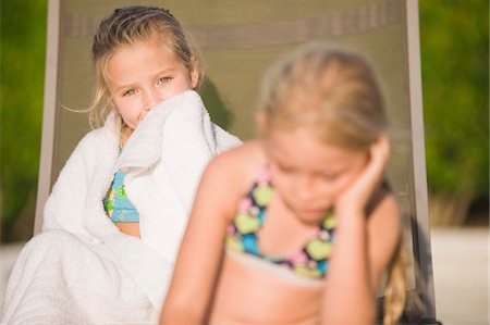 Two girls sitting on a lounge chair and ignoring each other Stock Photo - Premium Royalty-Free, Code: 6108-05873922