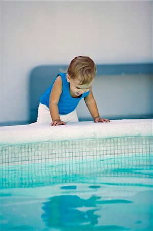 Baby boy looking into a swimming pool Stock Photo - Premium Royalty-Free, Code: 6108-05874056