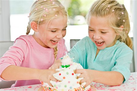 Two girls playfully inserting their hands in a birthday cake Stock Photo - Premium Royalty-Free, Code: 6108-05874095