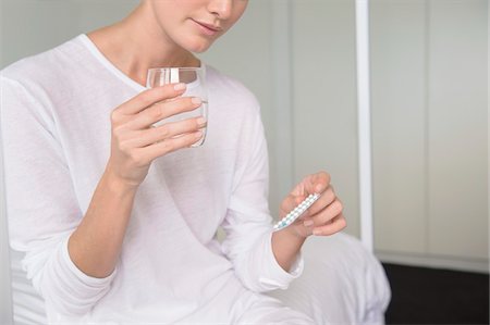 Woman holding a glass of water with a blister pack Stock Photo - Premium Royalty-Free, Code: 6108-05874171