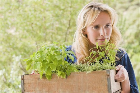 smelling hair - Woman carrying a crate of plants Stock Photo - Premium Royalty-Free, Code: 6108-05874186