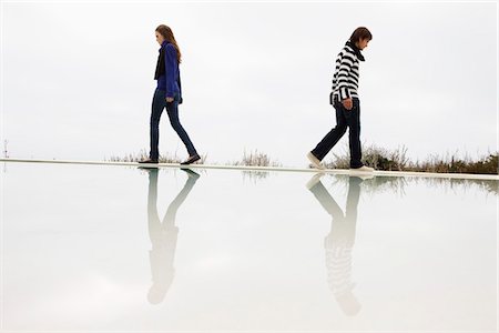 separation pictures lovers - Couple walking on the ledge of a swimming pool Stock Photo - Premium Royalty-Free, Code: 6108-05874270