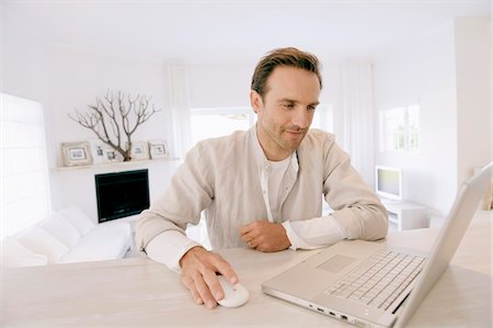 Man working on a laptop and smiling Stock Photo - Premium Royalty-Free, Code: 6108-05874353