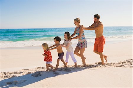 simsearch:6108-05859165,k - Family walking on the beach in train formation Foto de stock - Sin royalties Premium, Código: 6108-05874383