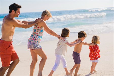 simsearch:6108-05866000,k - Famille marchant sur la plage dans la formation du train Photographie de stock - Premium Libres de Droits, Code: 6108-05874384