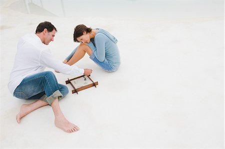 Couple playing with a sandbox Stock Photo - Premium Royalty-Free, Code: 6108-05874314
