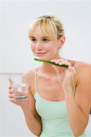 simsearch:6108-05873437,k - Woman holding a toothbrush with a glass of water Foto de stock - Sin royalties Premium, Código: 6108-05874477