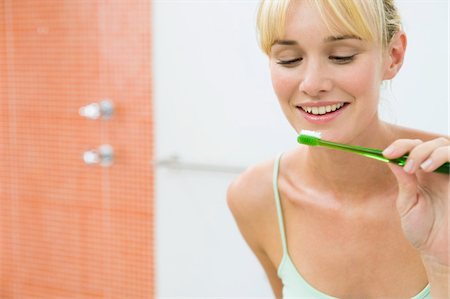 simsearch:6108-05856072,k - Reflection of a woman in the mirror holding a toothbrush Fotografie stock - Premium Royalty-Free, Codice: 6108-05874476