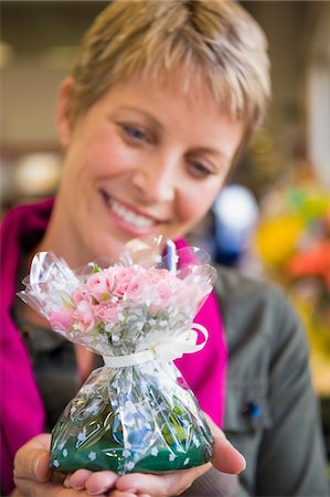Woman holding a bouquet of flowers and smiling Stock Photo - Premium Royalty-Free, Code: 6108-05874439