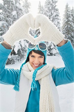 Young woman in winter clothes making heart shape with hands Stock Photo - Premium Royalty-Free, Code: 6108-05874559