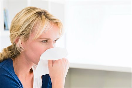 Close-up of a woman blowing her nose with a handkerchief Stock Photo - Premium Royalty-Free, Code: 6108-05874503