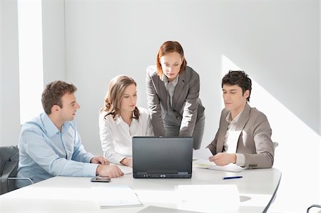simsearch:6108-05868312,k - Business executives looking at a laptop in a board room Stock Photo - Premium Royalty-Free, Code: 6108-05874684