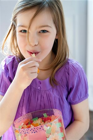 preteen girl brown hair blue eyes - Portrait of a girl eating gum drops Stock Photo - Premium Royalty-Free, Code: 6108-05874634