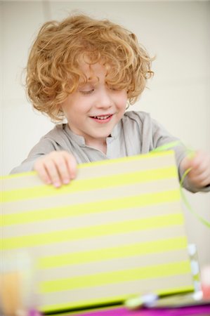 Boy opening his birthday present Stock Photo - Premium Royalty-Free, Code: 6108-05874759