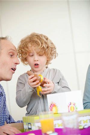 Boy opening his birthday present with his grandfather beside him Stock Photo - Premium Royalty-Free, Code: 6108-05874761