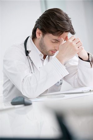 Male doctor sitting in his office and looking upset Stock Photo - Premium Royalty-Free, Code: 6108-05874764