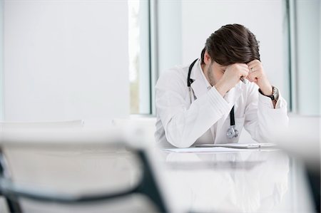 Male doctor sitting in his office and looking upset Stock Photo - Premium Royalty-Free, Code: 6108-05874765