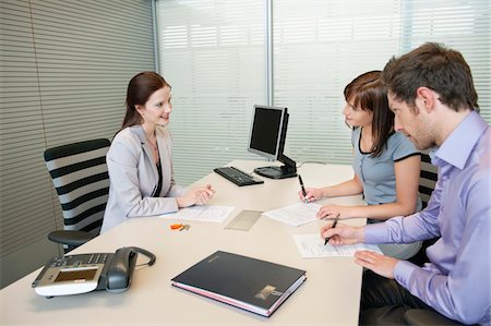 Couple signing agreement form in a real estate agent's office Stock Photo - Premium Royalty-Free, Code: 6108-05874735