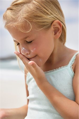 Girl applying sunscreen lotion on her face Stock Photo - Premium Royalty-Free, Code: 6108-05874912