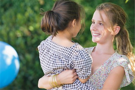 Cute girl carrying little sister and smiling Stock Photo - Premium Royalty-Free, Code: 6108-05874917
