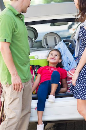 Cute little girl lying in car trunk while parents looking at her Stock Photo - Premium Royalty-Free, Code: 6108-05874933