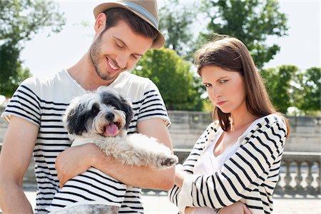 streicheln - Homme portant un chiot et souriant avec une femme à la recherche triste, Paris, Ile-de-France, France Photographie de stock - Premium Libres de Droits, Code: 6108-05875195