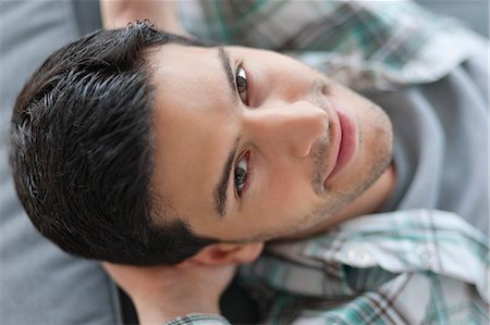 Man lying on a couch and smiling Stock Photo - Premium Royalty-Free, Code: 6108-06165971